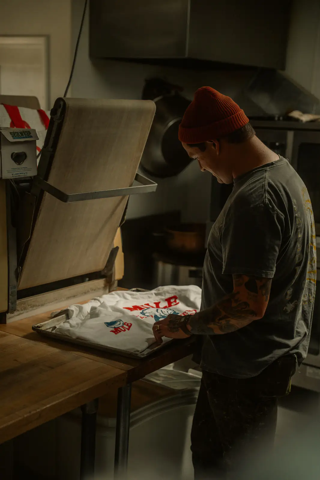 Print operator arranging a full-color shirt beside an open heat press
