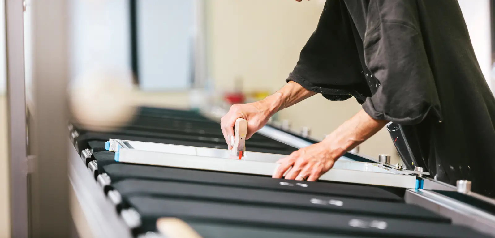 Screen-printing artisan pulling ink across a mesh screen with a squeegee